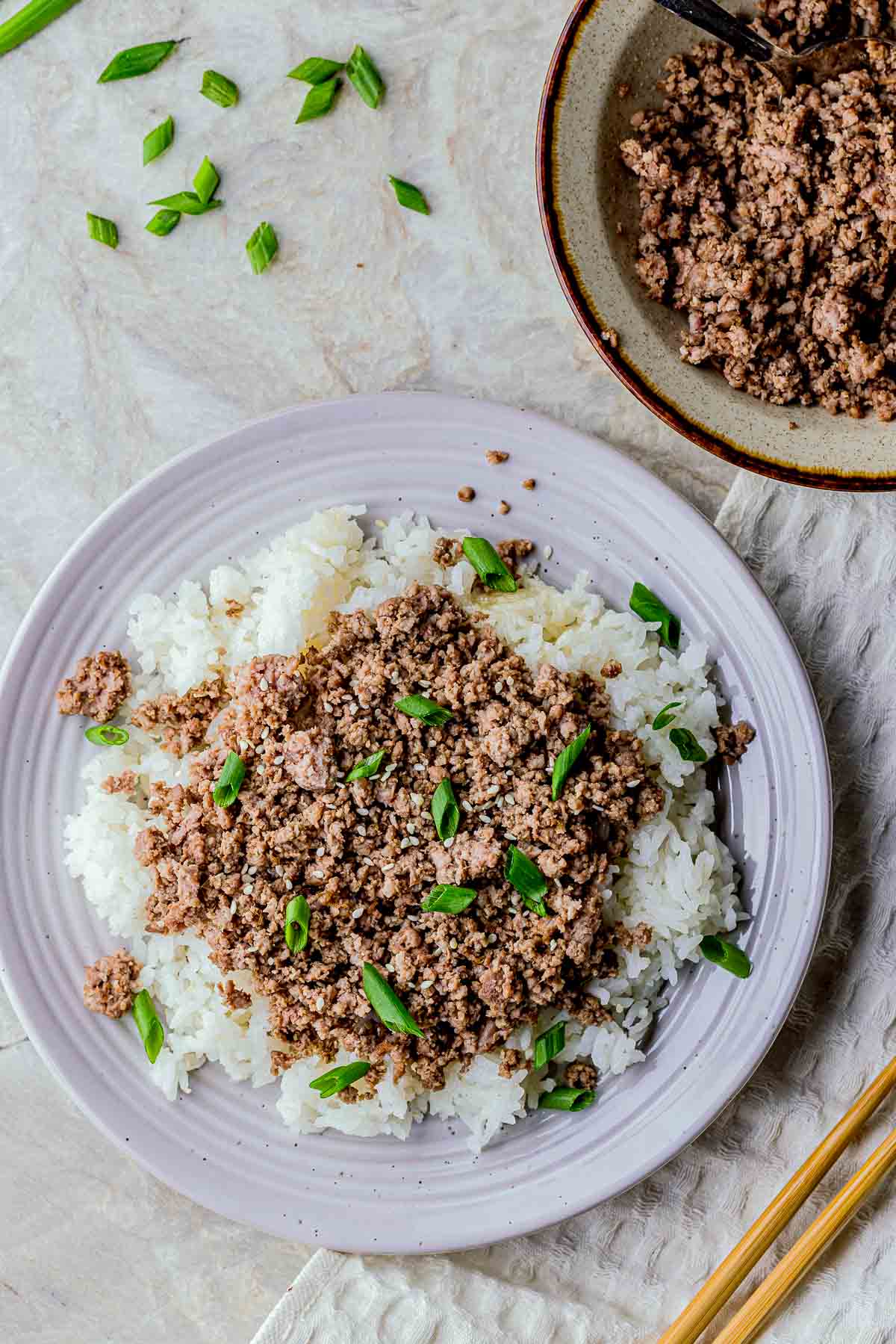 a plate of rice covered in ground beef and green onions