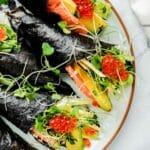 close up of sushi hand rolls with sprouts and salmon and roe