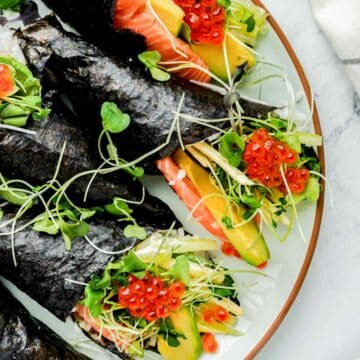 close up of sushi hand rolls with sprouts and salmon and roe