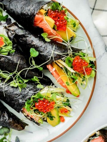 close up of sushi hand rolls with sprouts and salmon and roe