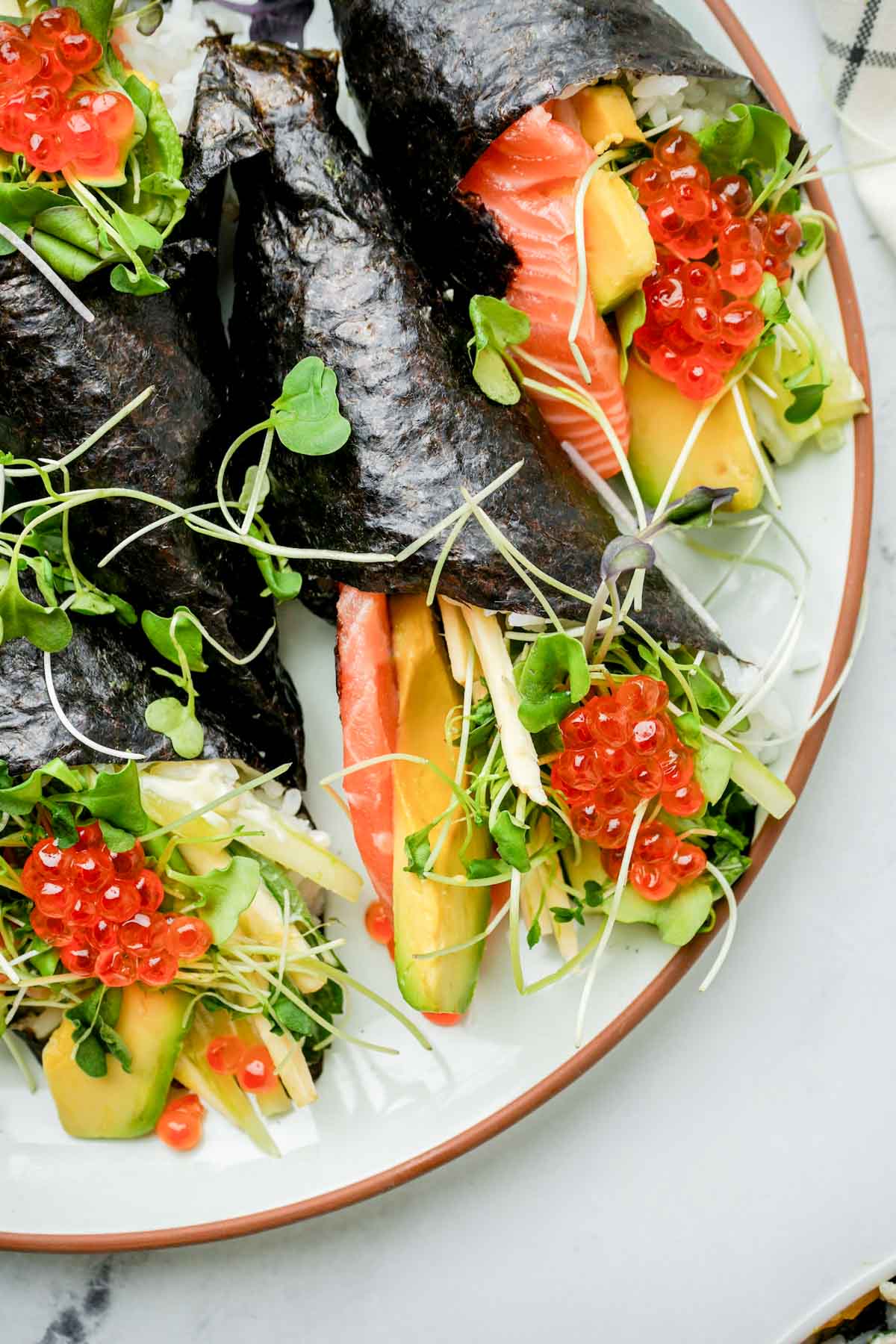 salmon, veggies and roe wrapped up in seaweed on a plate