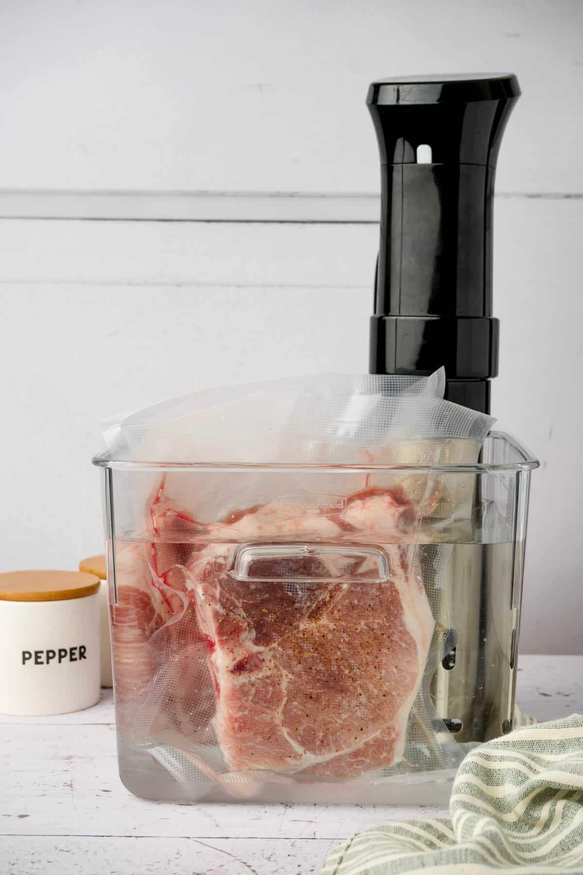 raw pork chops cooking in a sous vide water bath for sous vide pork chops