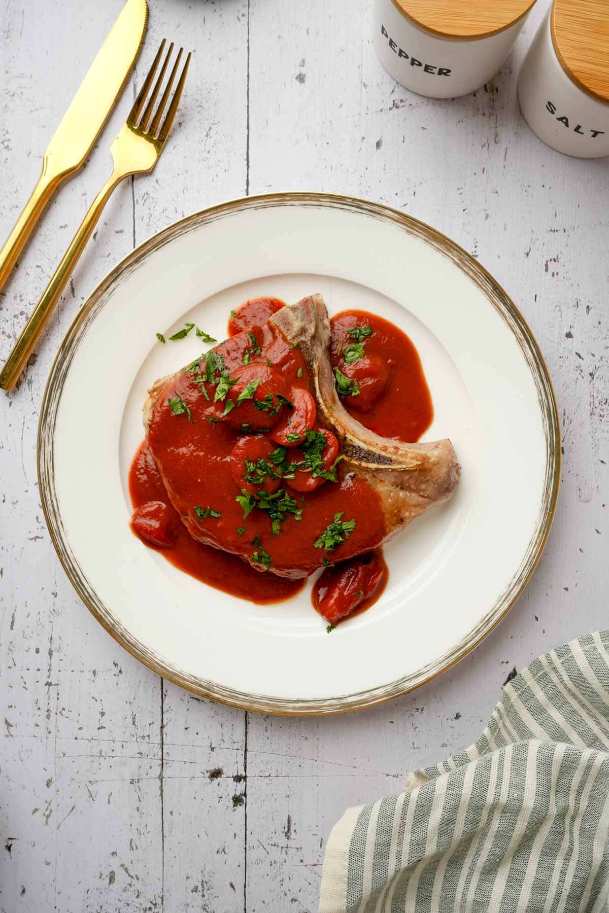 sous vide bone in pork chops on a plate smothered in tomato glaze and herbs