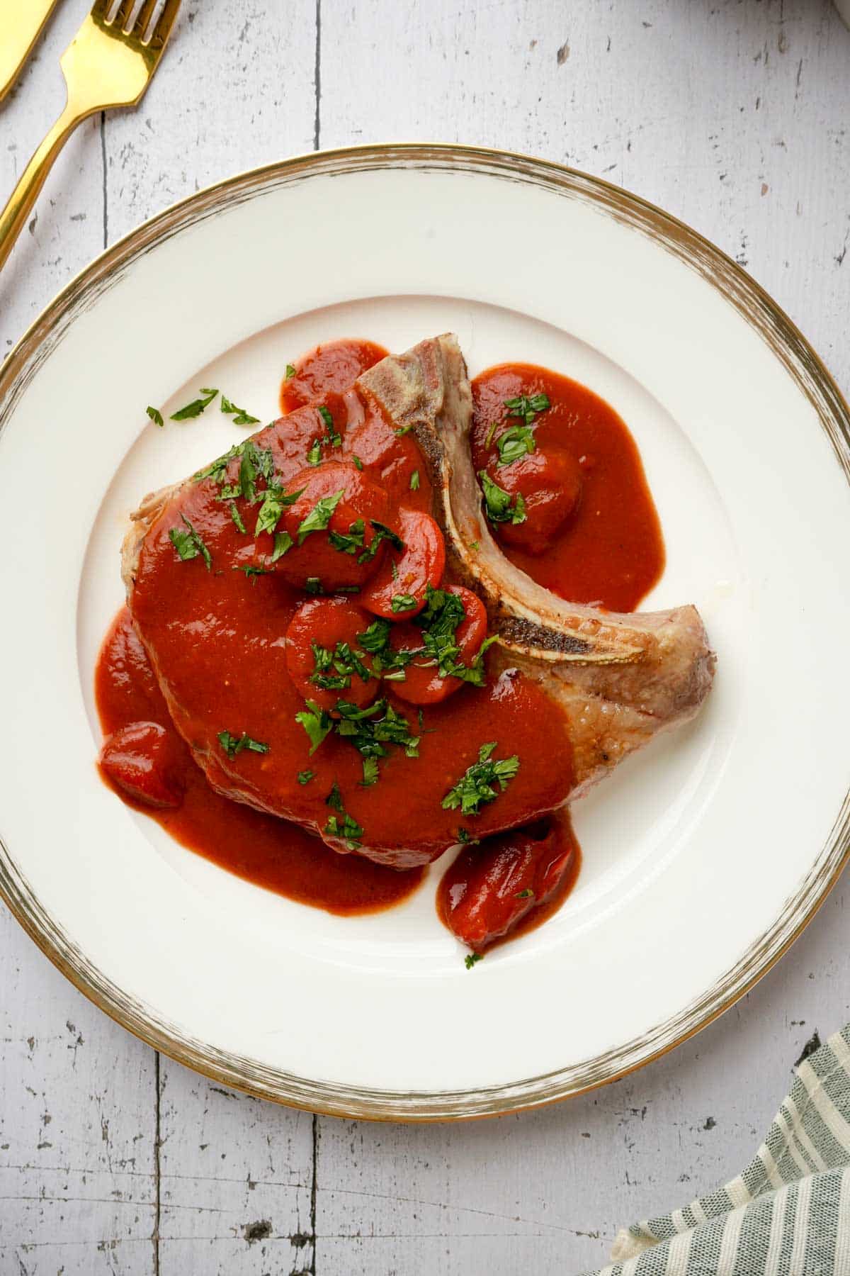 A glazed pork chops smothered in tomato sauce on a plate