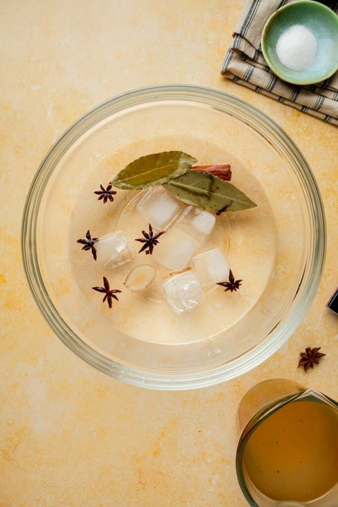 a glass bowl with whole spices and ice cubes in it