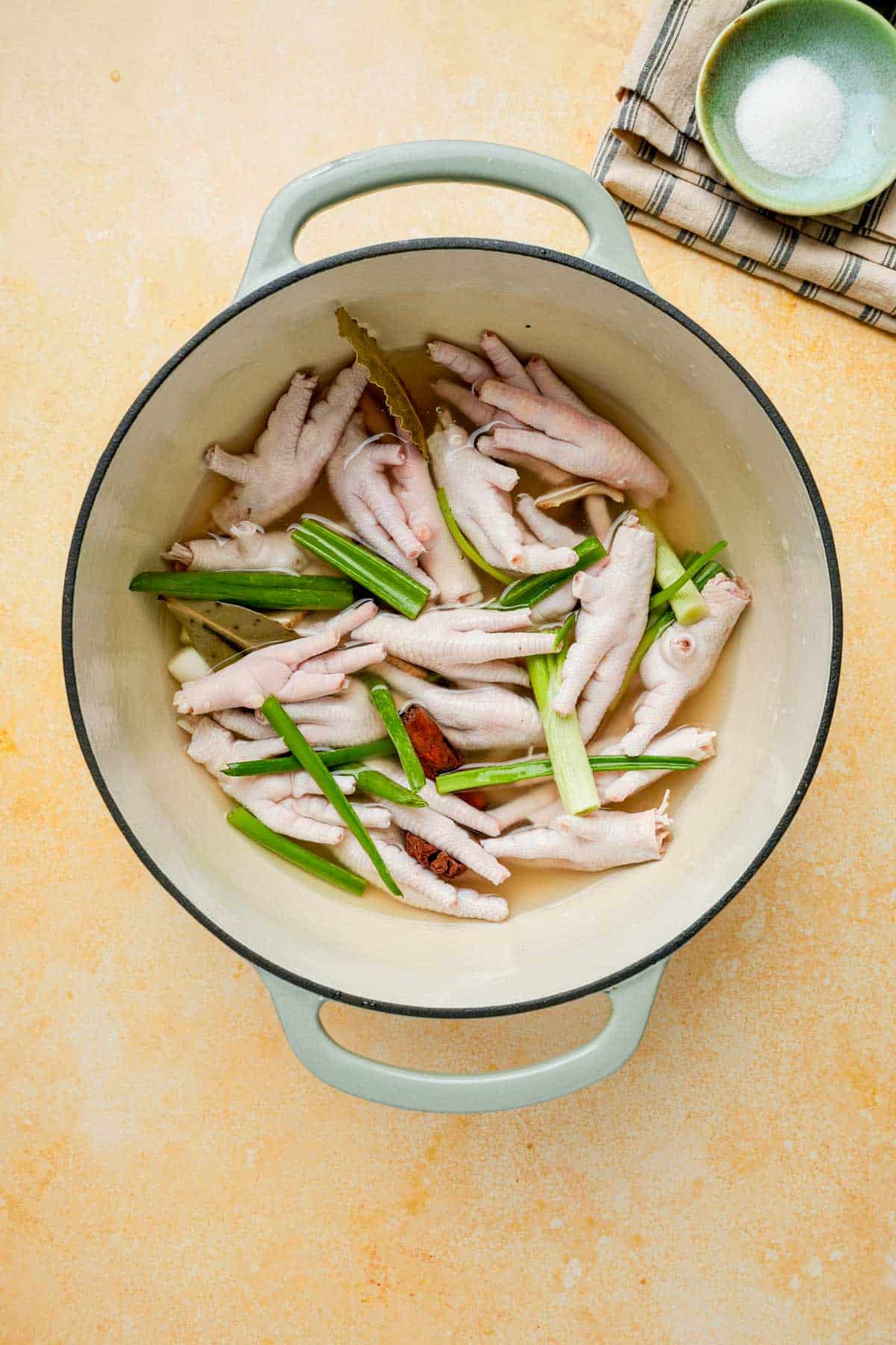 chicken feet in a pot with green onions and broth
