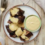 short ribs on a plate with yellow sauce