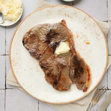a steak on a plate with butter on top