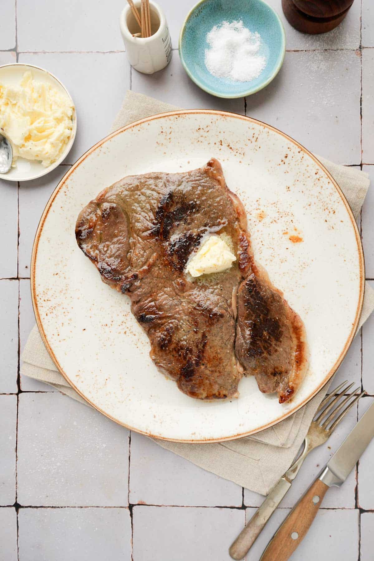 a steak on a plate with butter on top