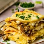 sliced mushroom lasagna on a plate garnished with herbs