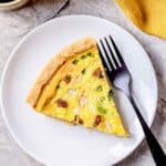 piece of sausage quiche on a plate with a fork.