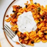 a plate of chili mac with sour cream on top.