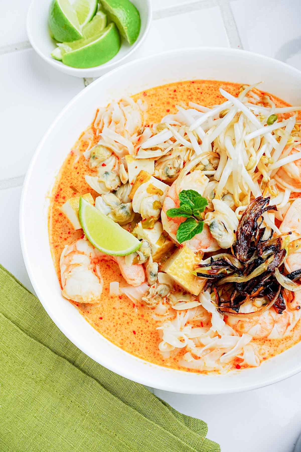 a bowl of singapore style laksa garnished with lime.