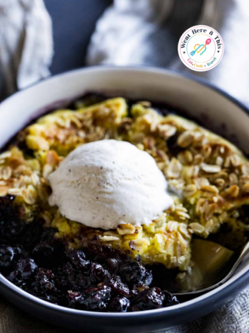 "Warm Instant Pot blueberry cobbler with an oat crumble topping and a scoop of melting vanilla ice cream.