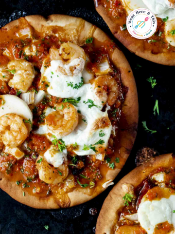 Homemade Brazilian flatbread pizza on pita crust topped with succulent sautéed shrimp, melted burrata cheese, hearts of palm, and vibrant roasted red pepper chimichurri sauce, garnished with fresh parsley.