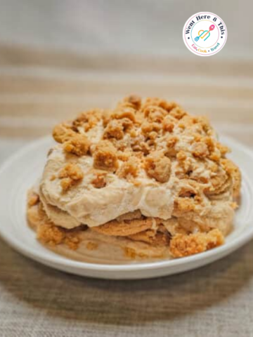A close-up shot of a single serving of a no-bake peanut butter icebox cake on a white plate, showcasing layers of creamy peanut butter filling and soft cookies topped with a generous pile of crushed peanut butter cookie crumbs.