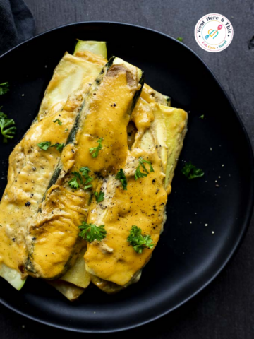 Slices of tender Roasted Squash and Zucchini smothered in a rich, creamy yellow mustard sauce with fresh parsley garnish on a round black plate for a healthy Father's Day side dish.