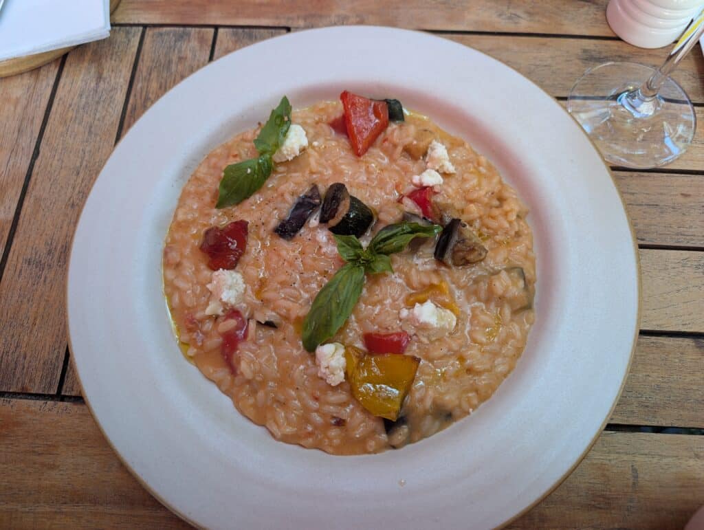 Ratatouille Risotto, a creamy risotto loaded with tomatoes, eggplant, and zucchini, then topped with fresh basil leaves and crumbled cheese.