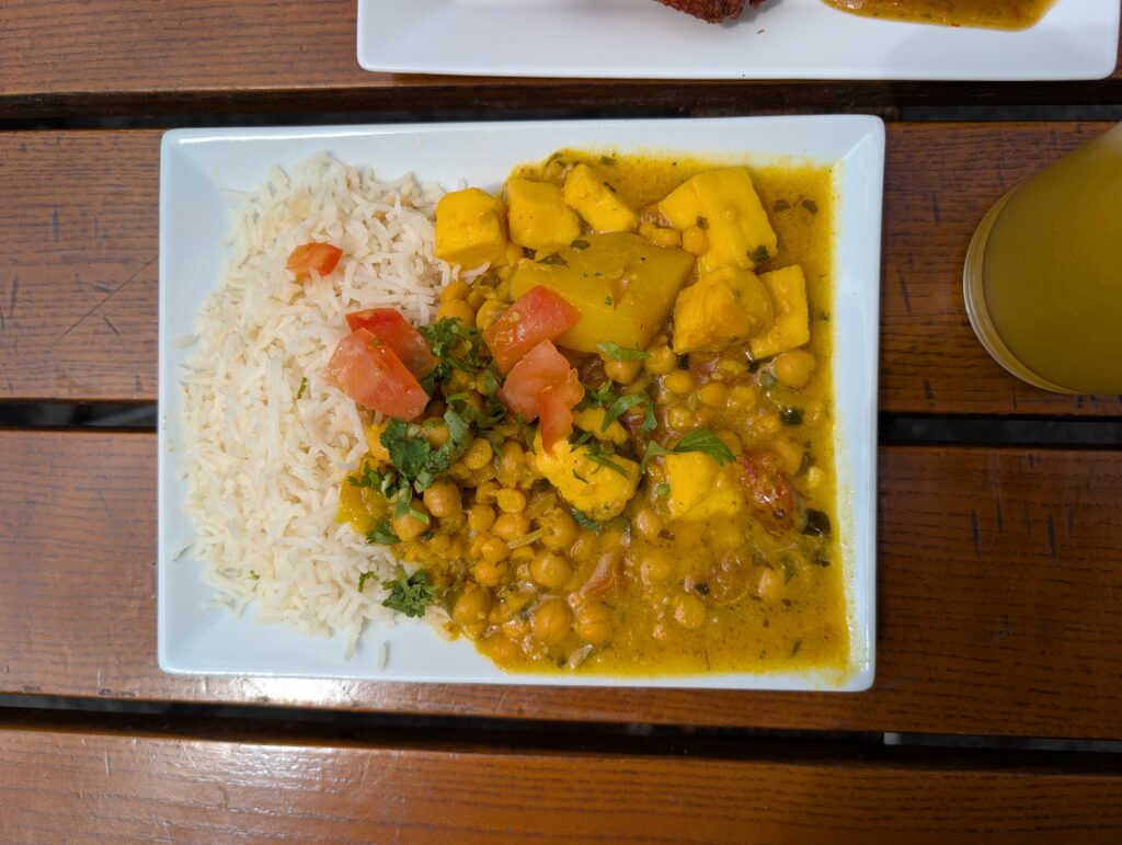 Chickpea Curry also known as chana masala, served alongside white basmati rice, and garnished with fresh tomatoes, and herbs.