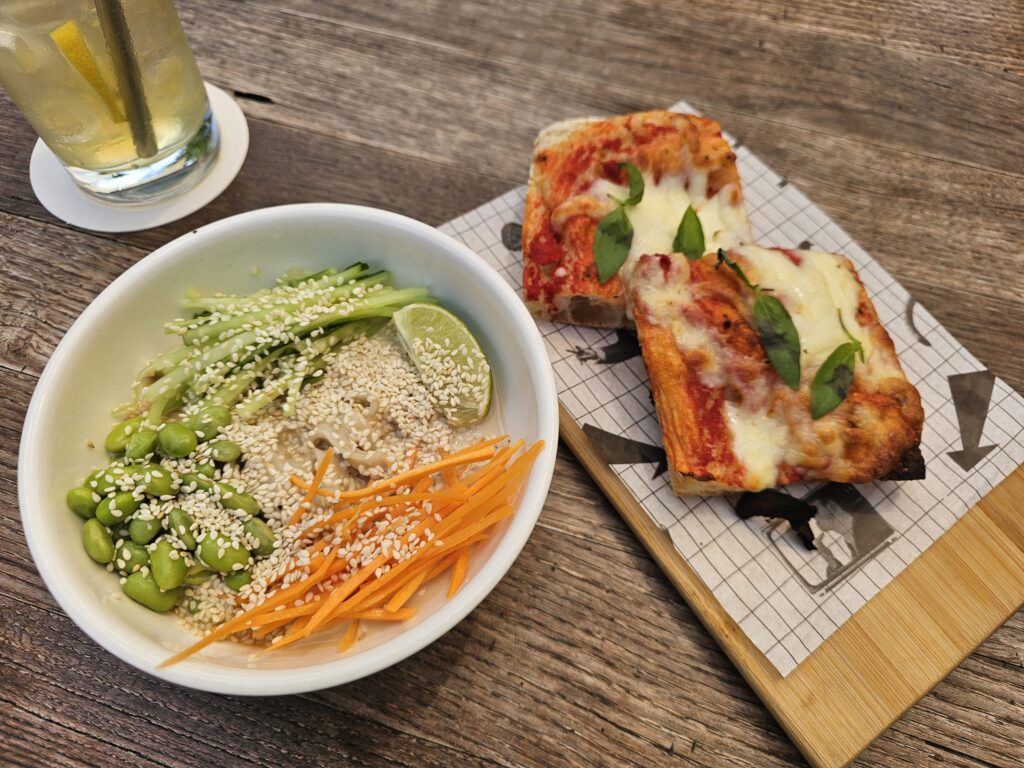 Margherita pizza with tomato sauce, mozzarella, basil, and oregano, along with a refreshing sesame cold noodle salad filled with carrots, cucumbers, edamame, and a flavorful sesame dressing.