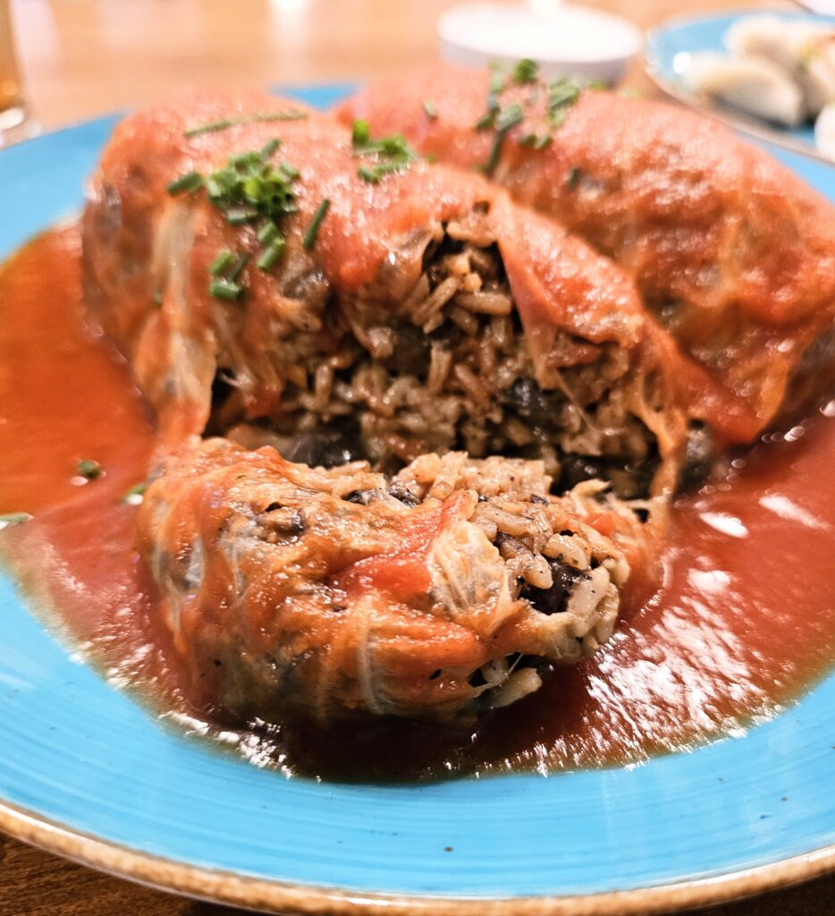 Cabbage roll filled with rice, mushrooms and vegetables and served with tomato sauce.