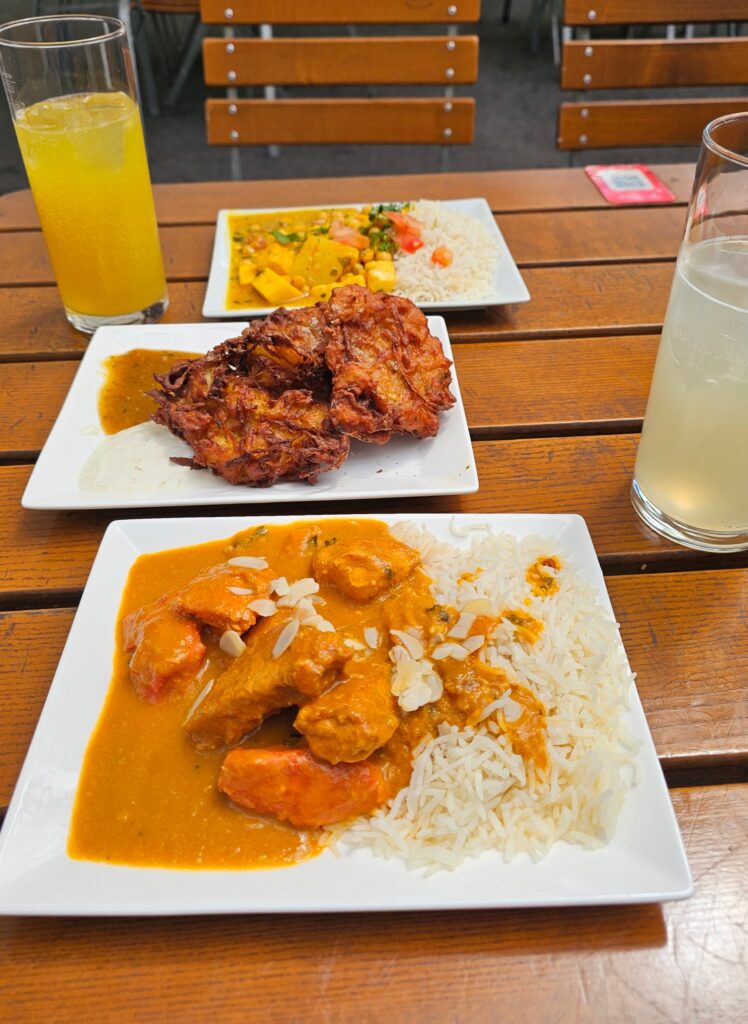 Chicken Tikka Masala also known as butter chicken in a rich, creamy orange-red tomato sauce with tender pieces of chicken garnished with sliced almonds served alongside a side of fluffy white basmati rice