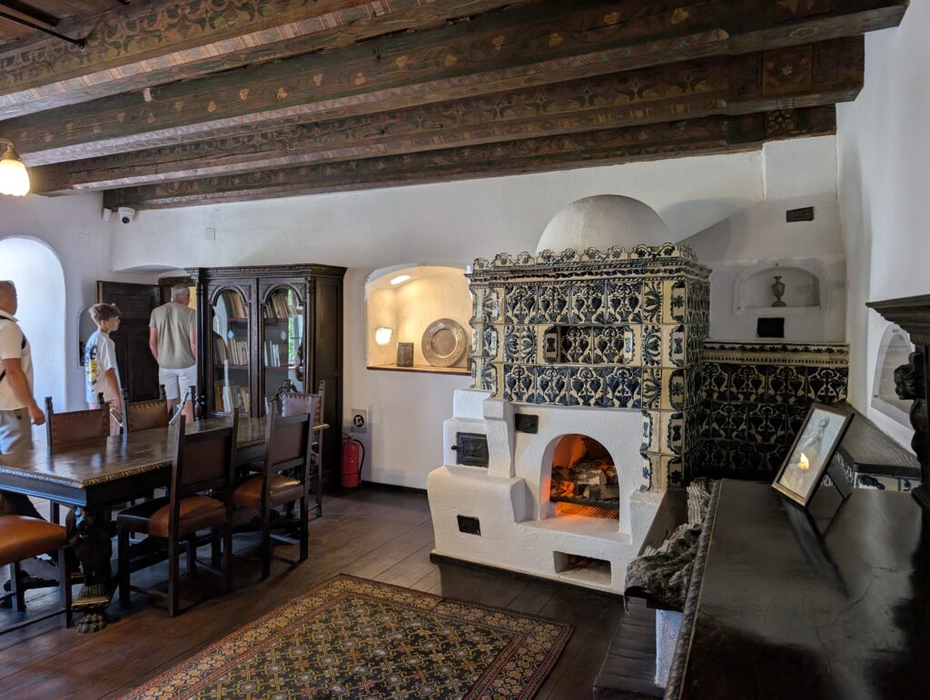 A glimpse inside Bran Castle, where a traditional ceramic-tiled stove and antique wooden furniture reflect the castle’s historic charm