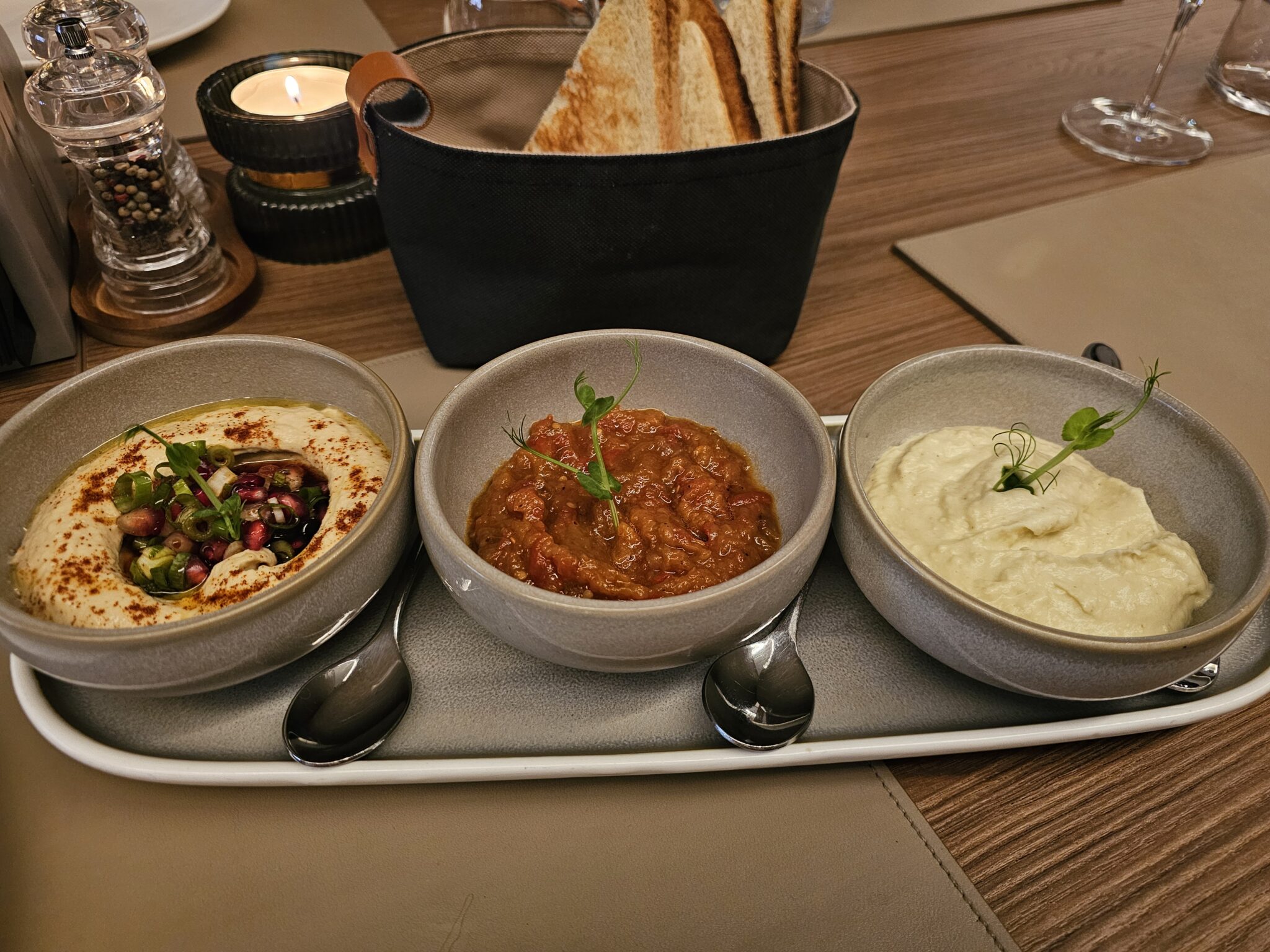 What I Ate in Romania: Hummus topped with pomegranate seeds and green onion with balsamic, a roasted vegetable spread, and an eggplant spread made with onion, green bell pepper, garlic, and spices.