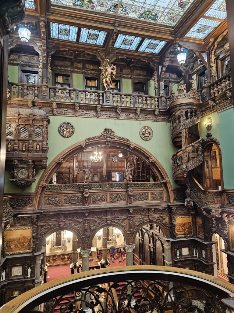 The ornate wooden interior hall and central staircase of the historic PeleÈ™ Castle
