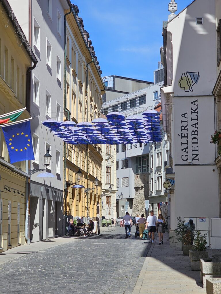 Nedbalova Street in Old Town (Staré Mesto), featuring the blue umbrella art installation. They love decorating streets like this in central Europe